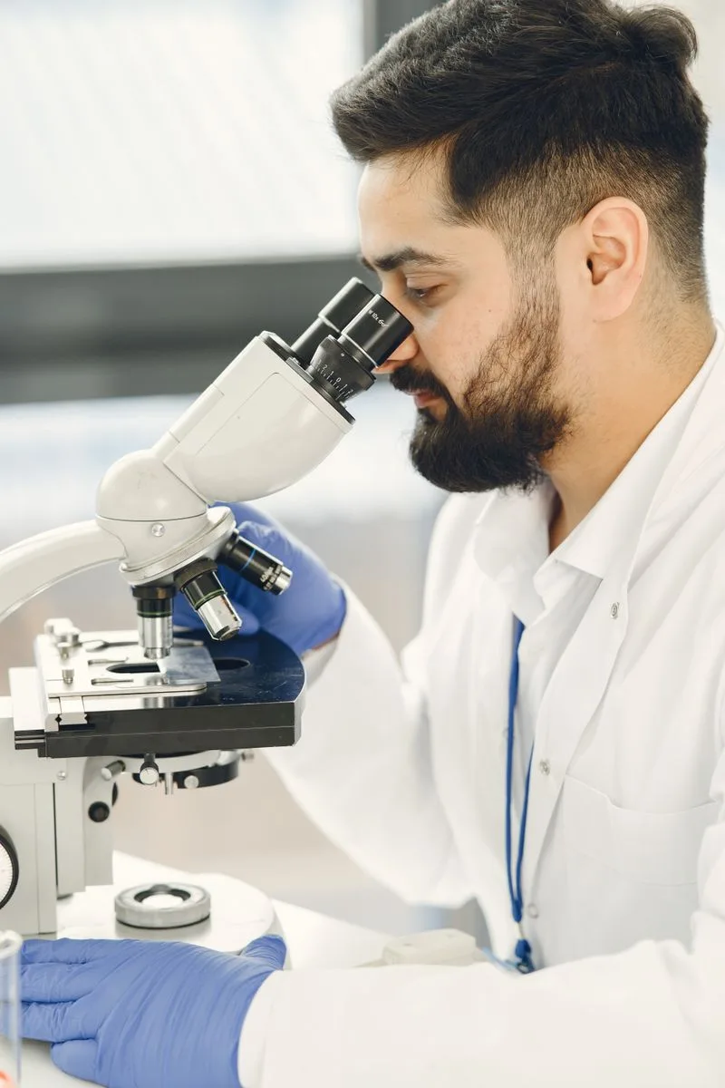 Scientist examining a sample through a microscope during early drug research